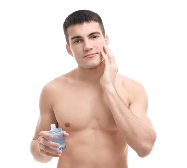 Красивый молодой человек, применяющий лосьон после бритья на белом фоне — стоковое фото