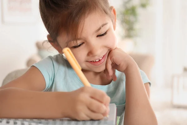 Милая маленькая девочка делает домашнее задание в помещении — стоковое фото