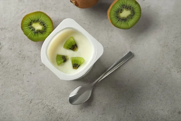 Plastic cup with yummy kiwi yogurt on table — Stock Photo, Image