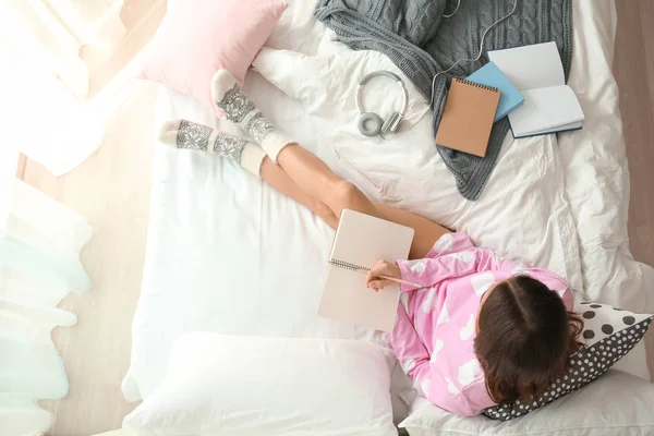 Jovem com caderno na cama em casa — Fotografia de Stock