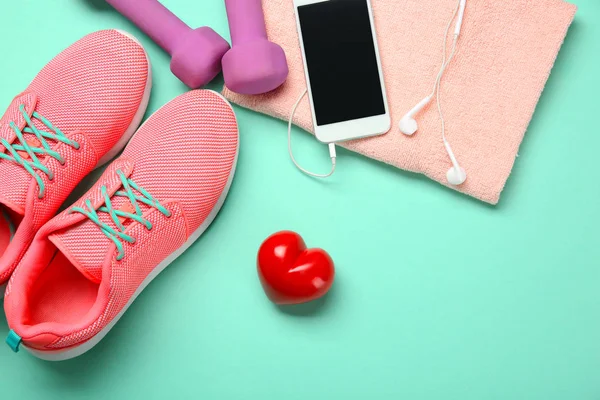 Cose da palestra, telefono e cuore rosso su sfondo a colori. Concetto di allenamento cardio — Foto Stock