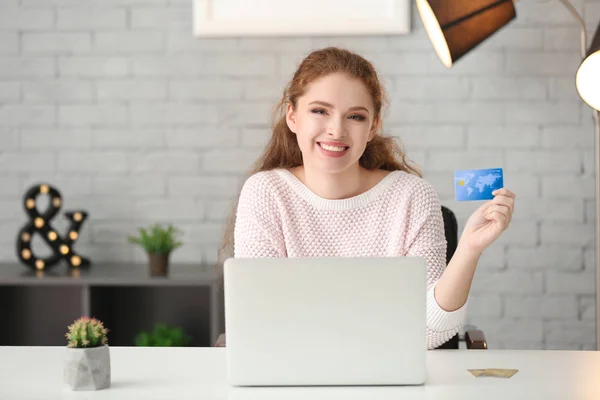 집에서 신용카드와 노트북을 가지고 온라인 쇼핑을 하는 젊은 여성 — 스톡 사진