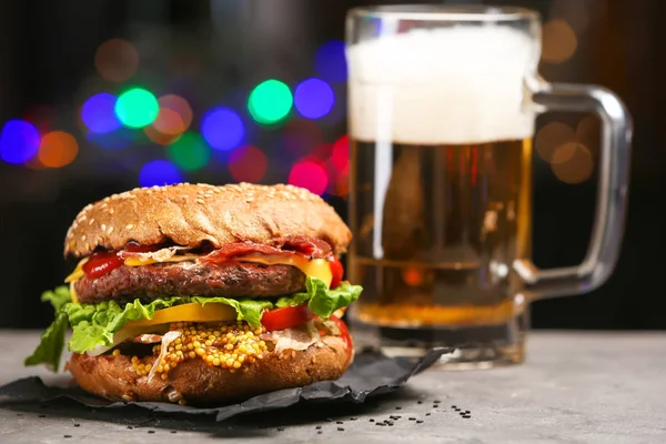 Tasty burger on slate plate against dark background — Stock Photo, Image