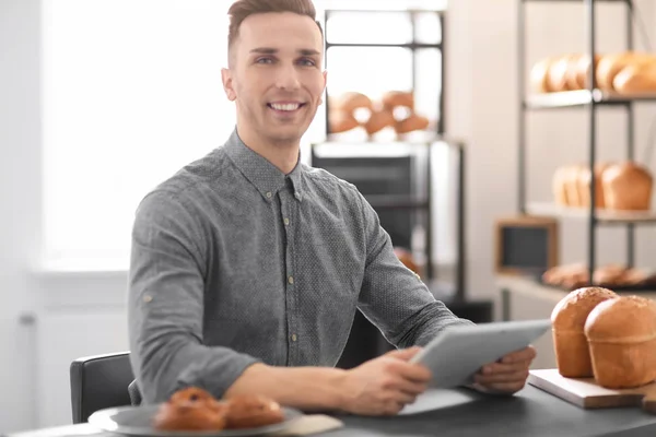 Hombre joven que usa tableta en la panadería. Dueño de pequeña empresa — Foto de Stock