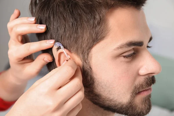 Médico poniendo audífono en el oído del hombre en interiores — Foto de Stock