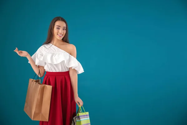 美しい若いです女性でショッピングバッグ上の色背景 — ストック写真