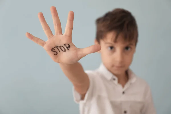 Little boy with word "Stop" on grey background — Stock Photo, Image