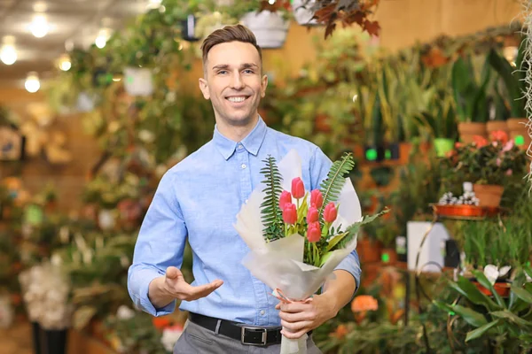 Portrét mladého muže s květinami ve skleníku. Majitel malé firmy — Stock fotografie