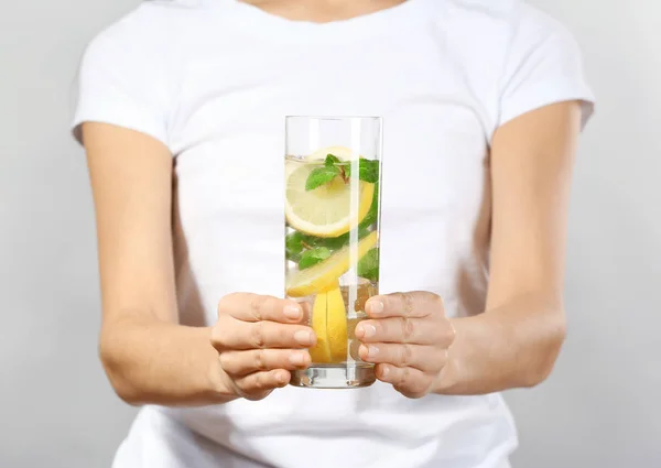 Jovem com copo de limonada em fundo cinza, close-up — Fotografia de Stock