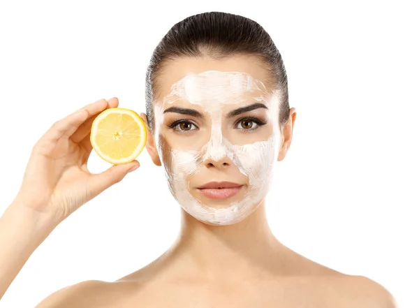 Wanita muda cantik dengan masker wajah dan setengah lemon matang di latar belakang putih — Stok Foto