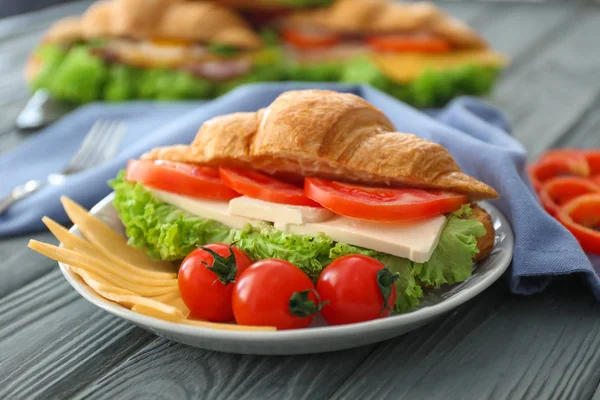 Teller mit leckerem Croissant-Sandwich auf dem Tisch — Stockfoto