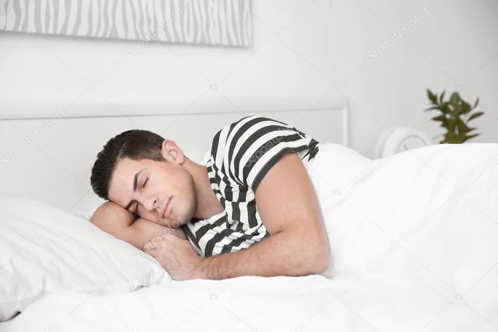Young handsome man sleeping in bed at home
