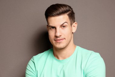 Gri arka plan üzerinde yükseltilmiş kaş ile genç adam