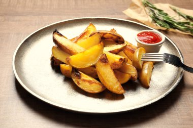 Lezzetli fırında patates dilimleri ve masada sos ile plaka