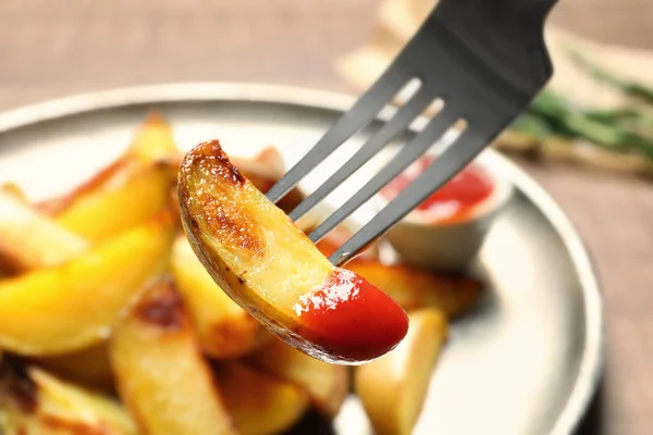 Fork with delicious baked potato wedge and sauce, closeup