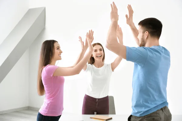 Junge Leute, die sich im Haus gegenseitig hohe fünf geben. Einheitskonzept — Stockfoto