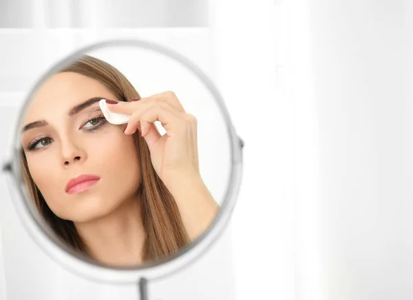 Mulher jovem removendo maquiagem na frente do espelho dentro de casa. Problema de perda de cílios — Fotografia de Stock