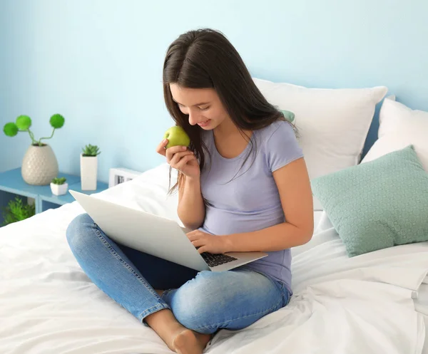 Cute teenager girl using laptop while doing homework in bedroom — Stock Photo, Image