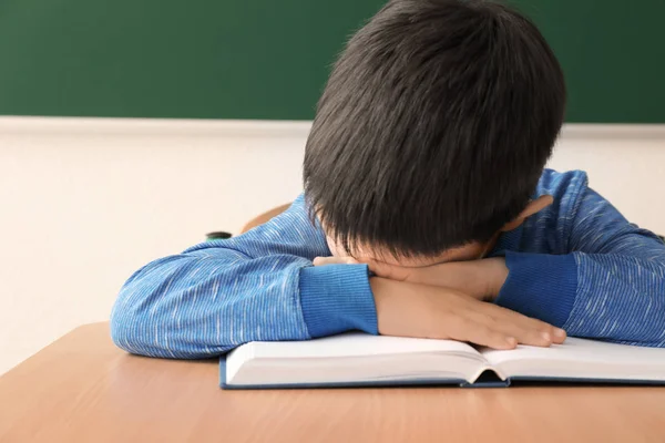 Spící chlapeček nebaví dělat domácí úkoly v učebně — Stock fotografie