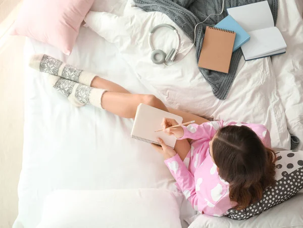 Junge Frau mit Notizbuch zu Hause im Bett — Stockfoto