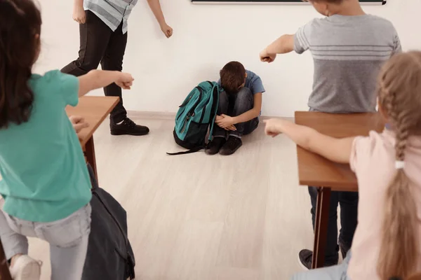 Chico intimidado sentado en el piso en el aula — Foto de Stock