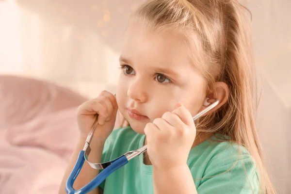 Carina bambina che gioca con lo stetoscopio a casa — Foto Stock