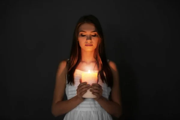 Piękna młoda kobieta z płonącą świecą w ciemności — Zdjęcie stockowe