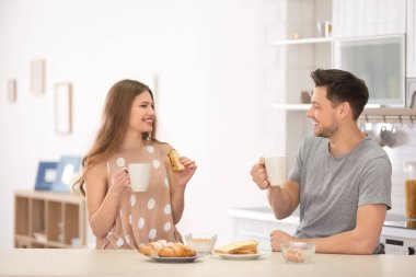 Genç çift mutfakta kahvaltı yapıyor.