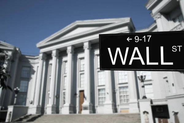 Wall Street signboard and stock exchange building on background