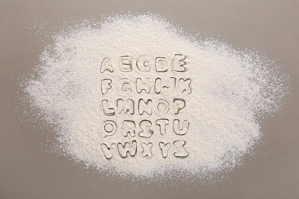 Silhouettes of alphabet letters on scattered flour