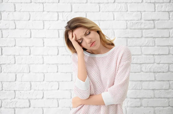 Portrait of beautiful emotional woman on brick wall background