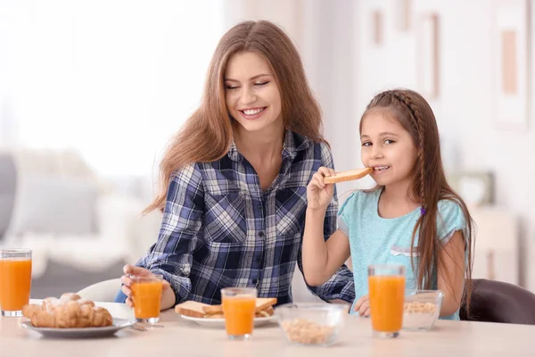 Mãe com filha tomando café da manhã na cozinha — Fotografia de Stock