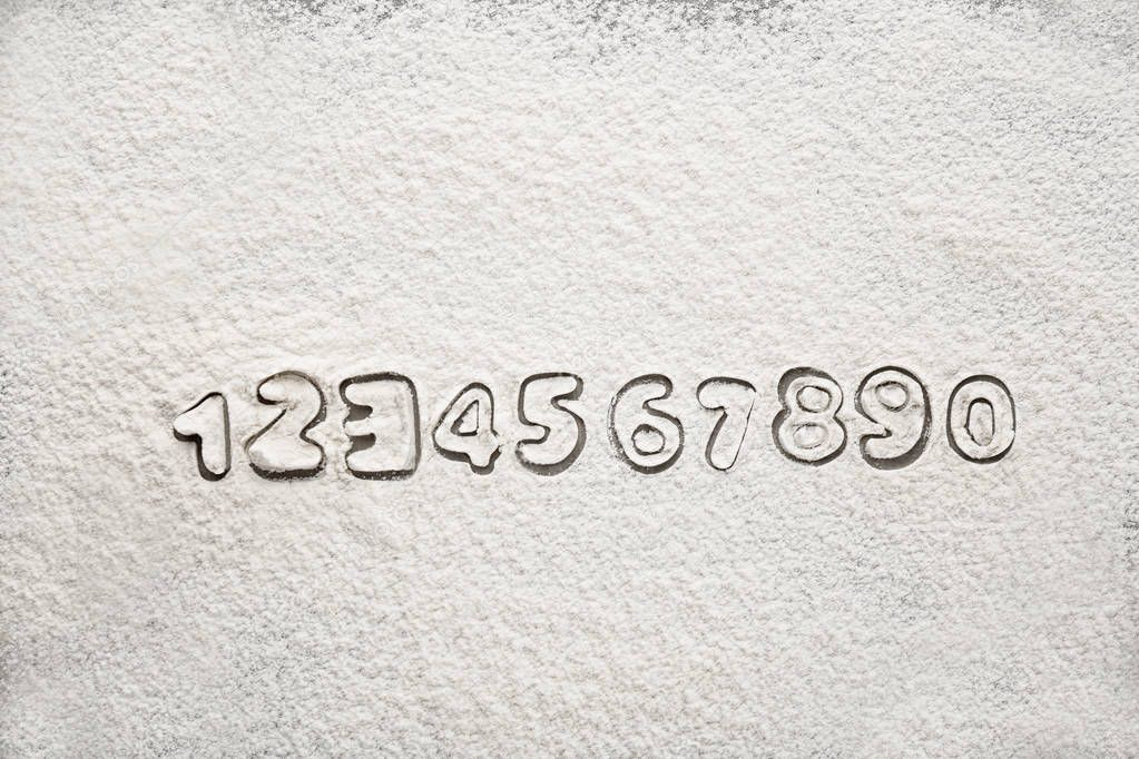 Silhouettes of Arabic numerals on scattered flour