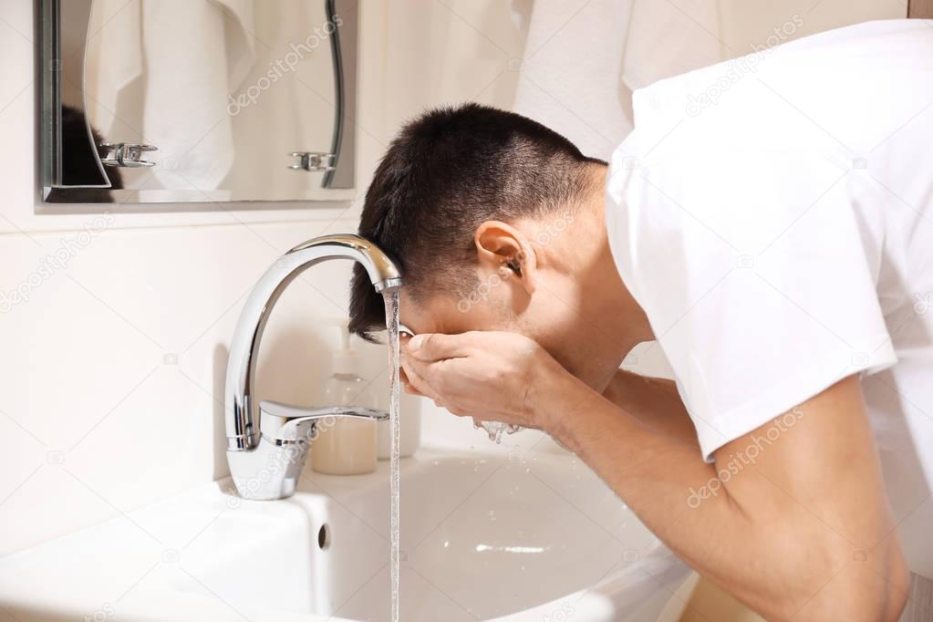 Man washing his face after shaving in bathroom