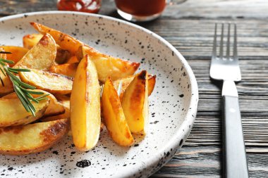 Lezzetli fırında patates dilimleri üzerinde ahşap masa ile plaka