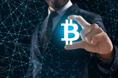 Sanal bitcoin sympol koyu arka plan üzerinde tutan işadamı