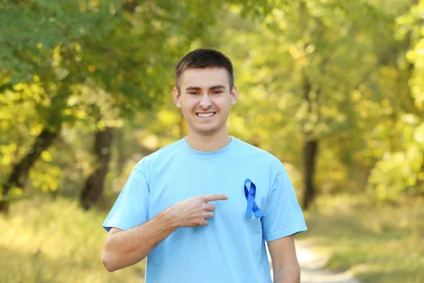 Joven apuntando a la cinta azul en su camiseta al aire libre. Concepto de conciencia del cáncer de próstata — Foto de Stock