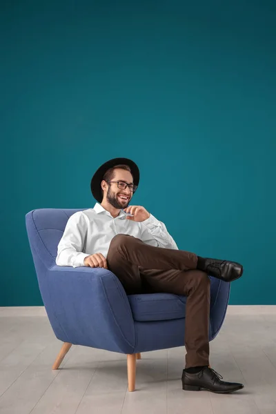 Przystojny Mężczyzna Siedząc Wygodnym Fotelu Kolorów Muru — Zdjęcie stockowe