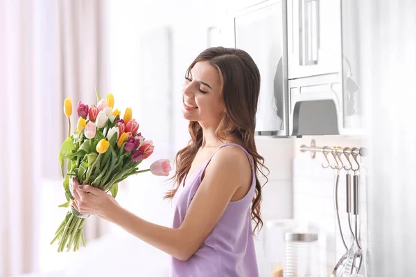 Piękna kobieta z bukietem tulipanów w domu — Zdjęcie stockowe