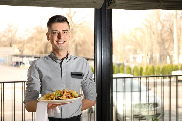 Handsome waiter with plate of salad at restaurant — Stock Photo, Image