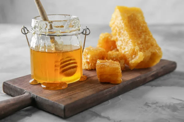 櫛と木の板の上に甘い蜂蜜の瓶 — ストック写真