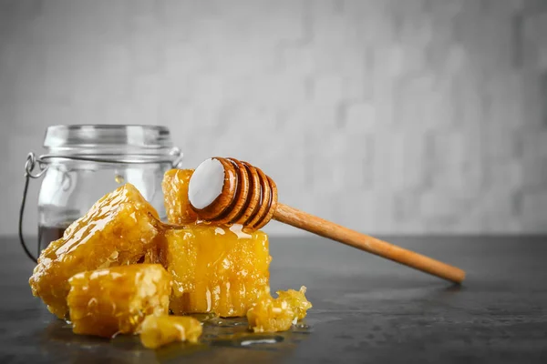 灰桌上加了一罐蜜蜂蜜的梳子 — 图库照片