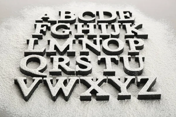 Алфавитные буквы на разбросанной муке — стоковое фото