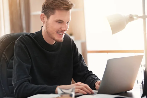 Junger Mann arbeitet mit Laptop drinnen — Stockfoto