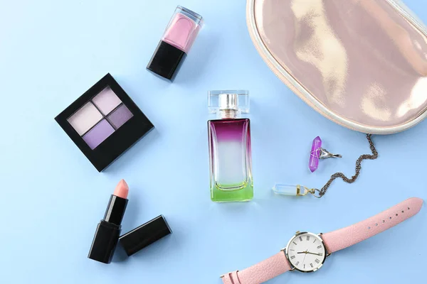 Bottle of perfume, accessories and cosmetic products on light background