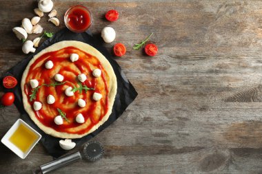 Mutfak masasında malzemelerle pizza için çiğ hamur