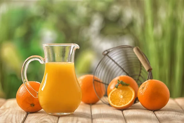 户外木桌上的鲜橙汁玻璃壶 — 图库照片