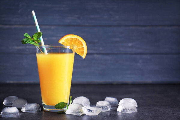 Glass of fresh orange juice with ice on table