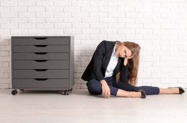 Kat beyaz tuğla duvarın üzerinde oturan şık elbiseli güzel moda kadın