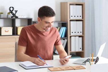 Ofiste çalışan cep telefonu ile genç adam